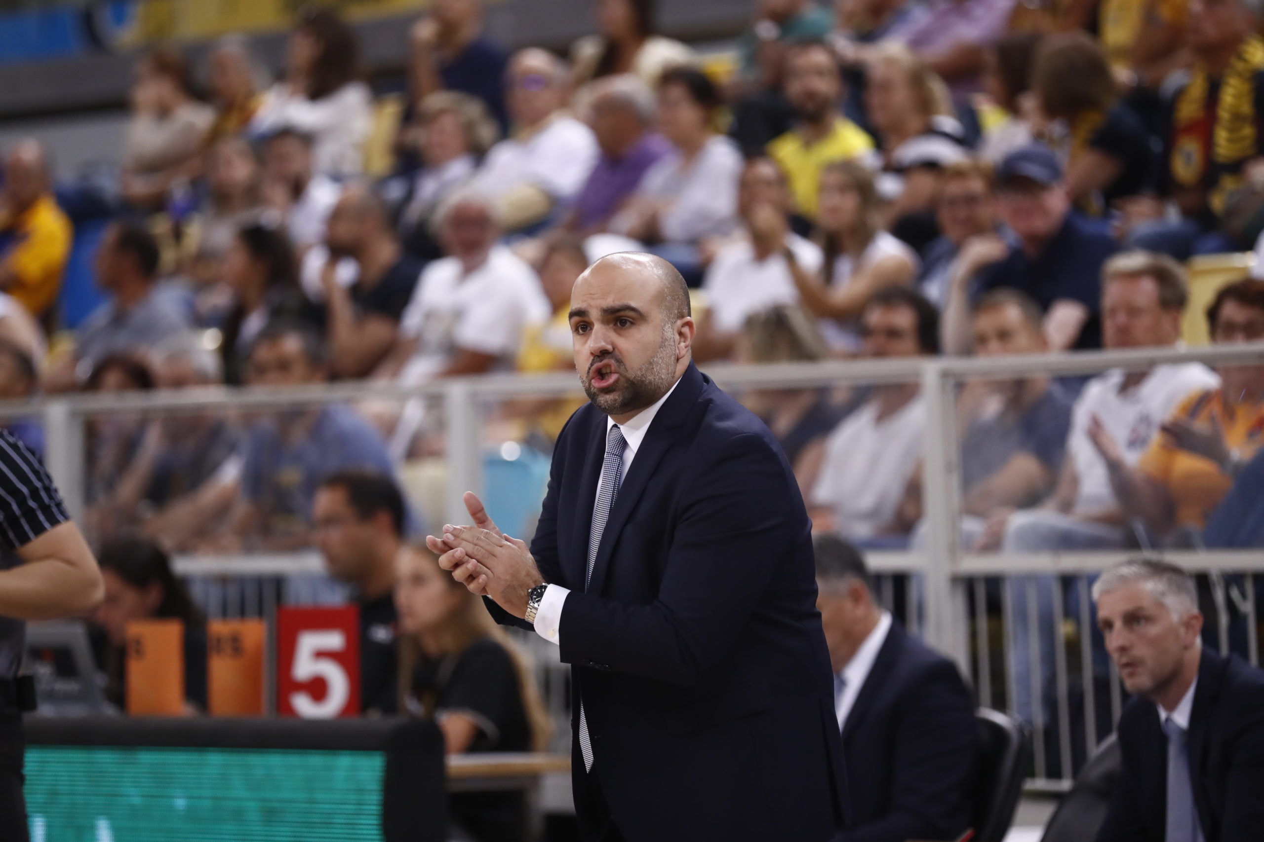Entrenador Victor García dirigiendo a su equipo ante un público animado.