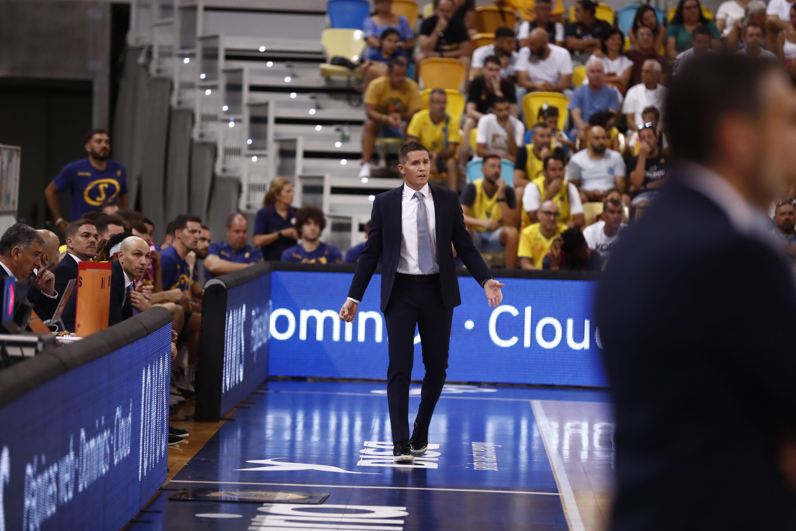 Entrenador Jaka Lakovic dirigiendo a su equipo durante un partido, con espectadores al fondo.