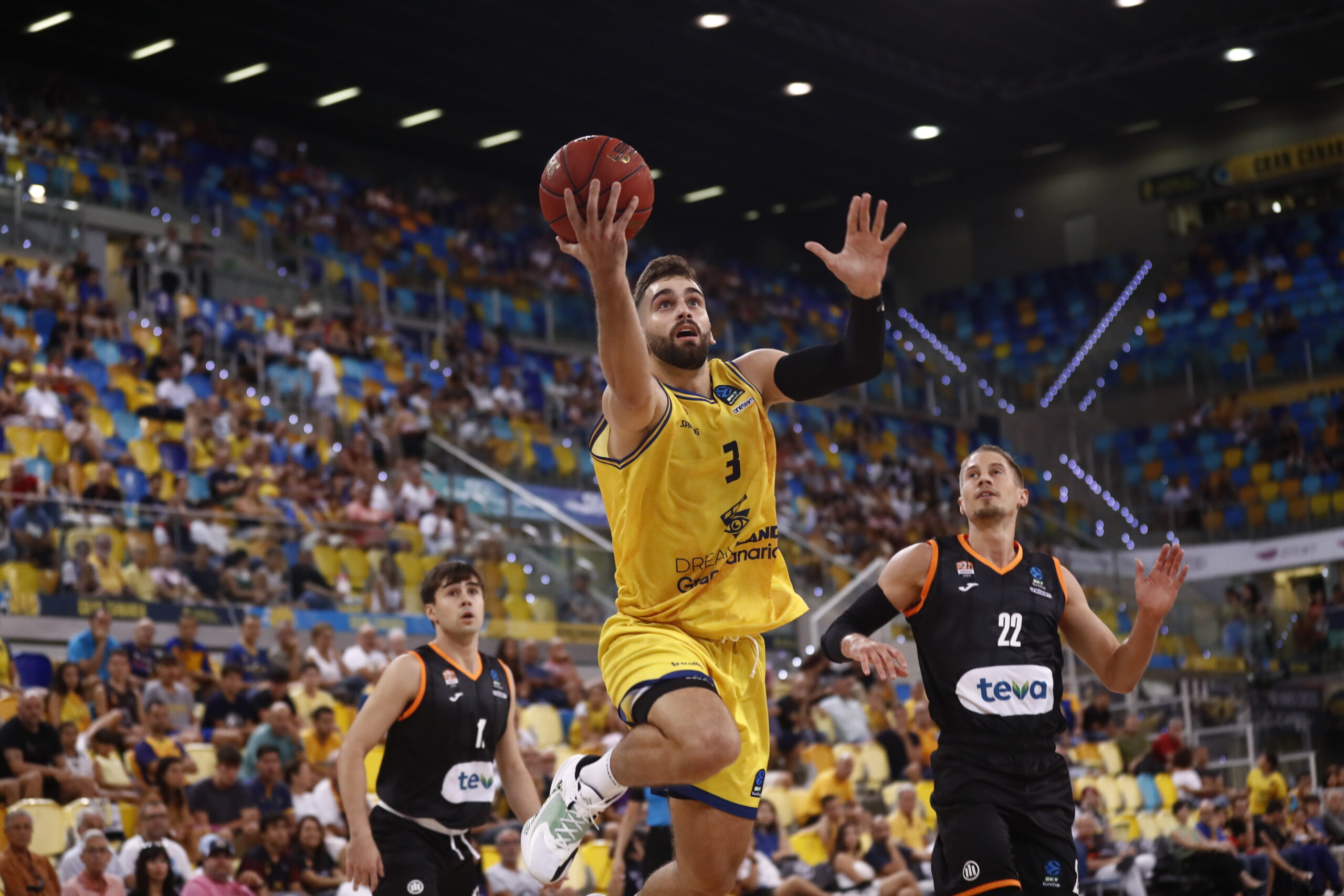 Jugador del Dreamland Gran Canaria lanza a canasta en un partido lleno de público.