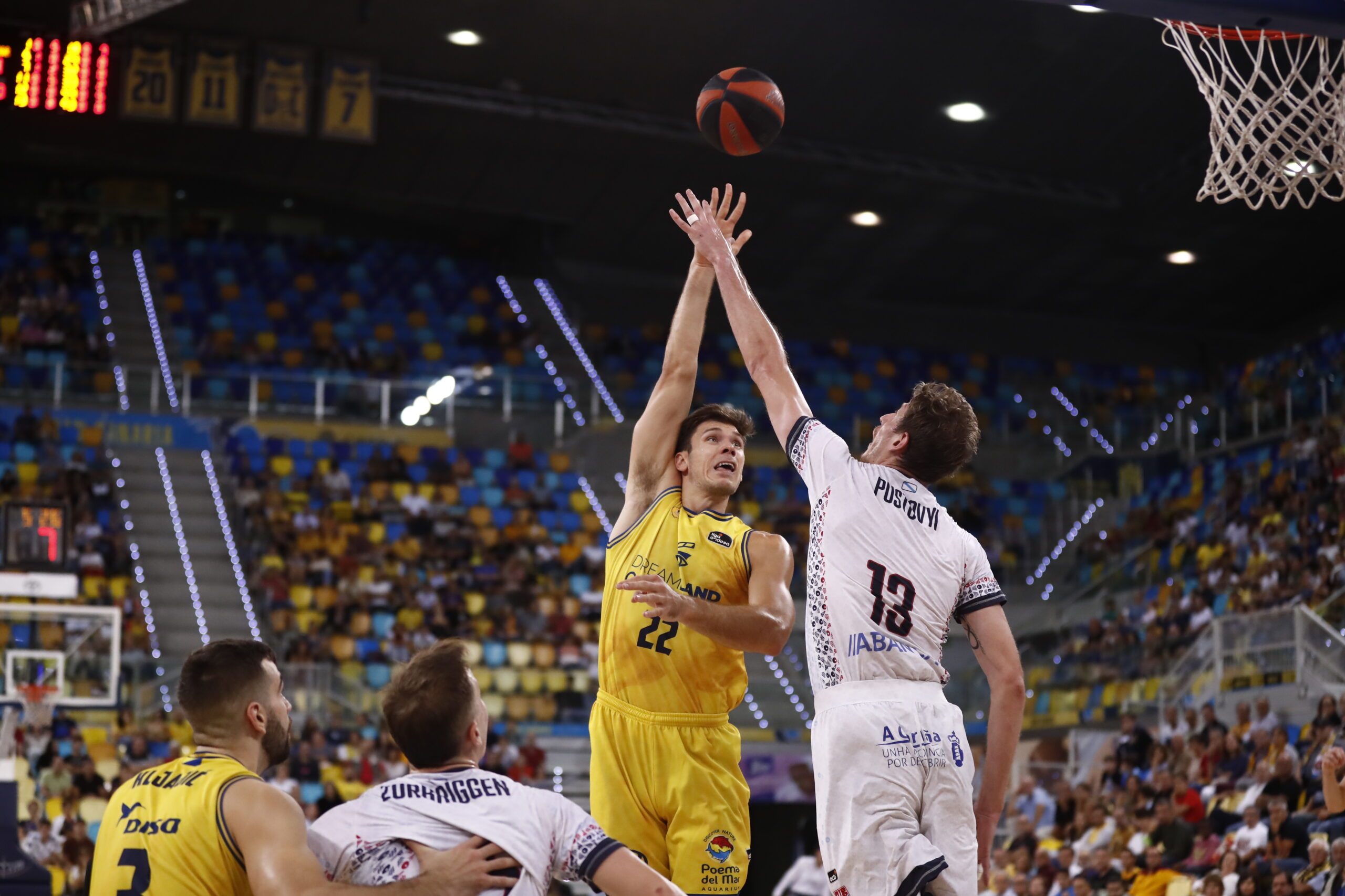 Jugador del Dreamland Gran Canaria lanza a canasta en un partido. Público de fondo.