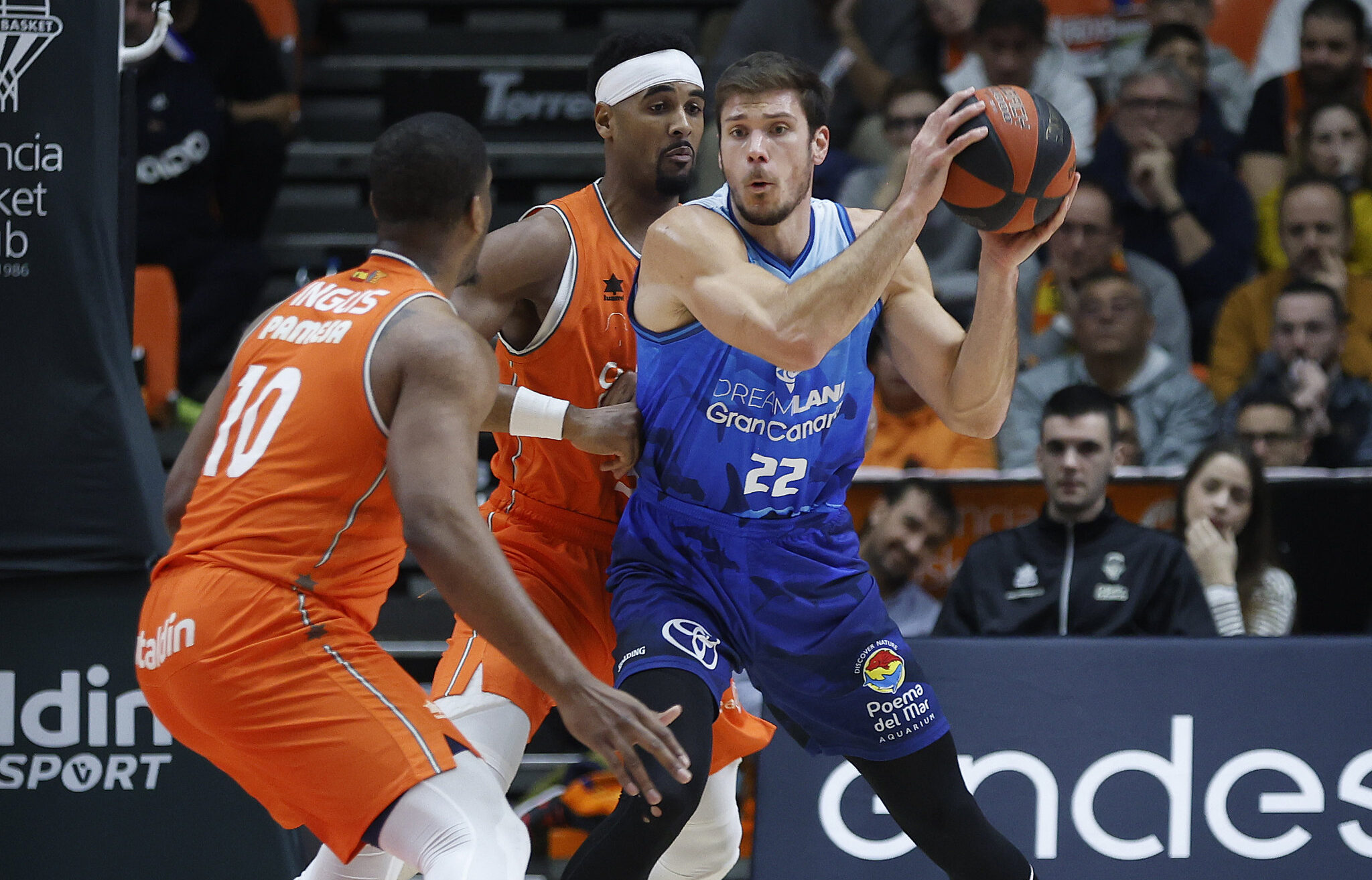 Jugador del Gran Canaria en acción, driblando con el balón ante defensores rivales.