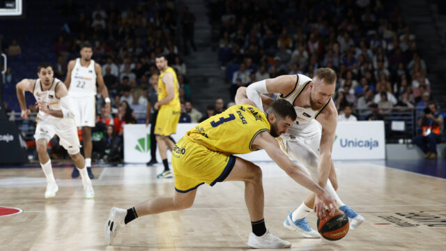 Juego intenso entre dos equipos de baloncesto, ambos luchando por el balón.