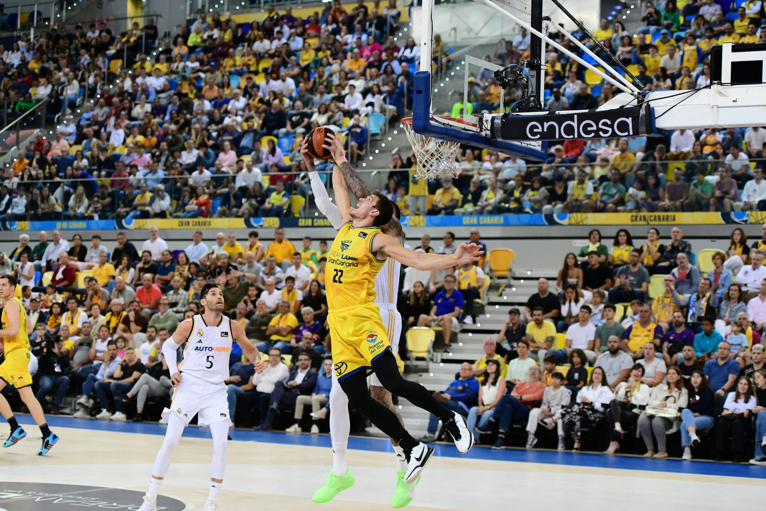 Jugador en acción realizando un mate durante un vibrante partido de baloncesto.