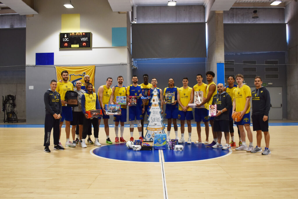 Jugadores del Club Baloncesto Gran Canaria posan con regalos para el Árbol de los Sueños.