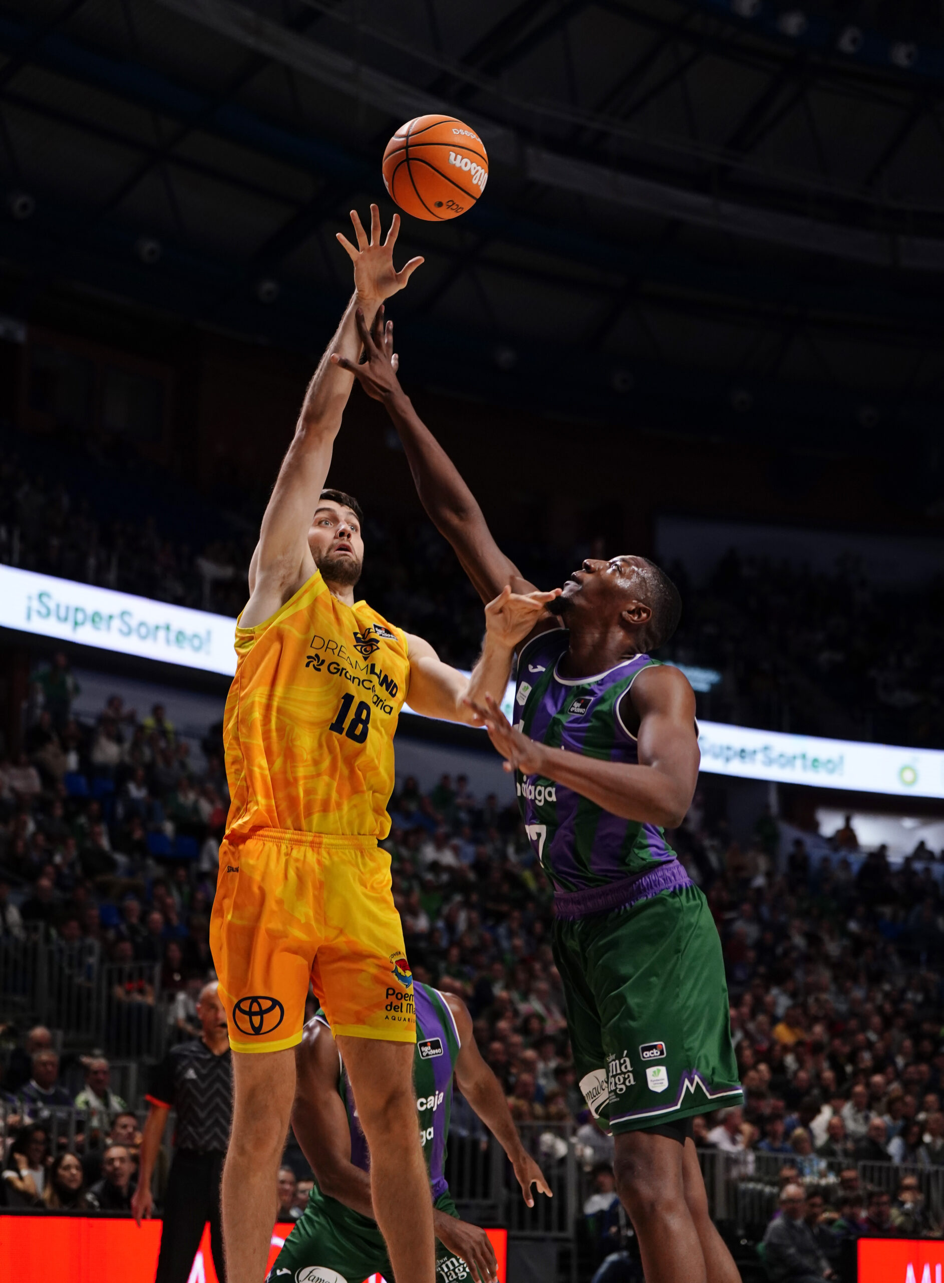 Jugador del Gran Canaria lanza a canasta bajo la defensa de un oponente en el Carpena.