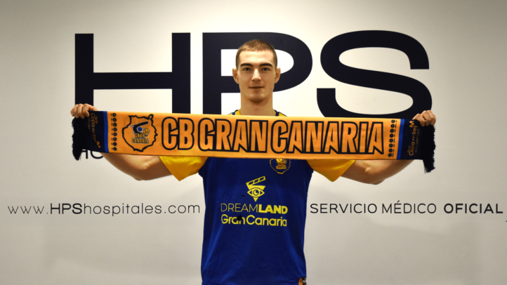 ya en la isla: ""Siempre doy el máximo, es mi forma de ser""","Jugador sosteniendo una bufanda del CB Gran Canaria, sonriendo en una sala.