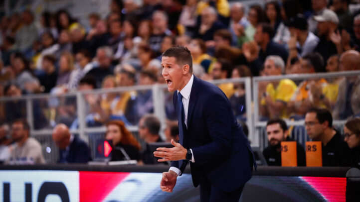 Entrenador gesticulando durante un partido, enfocado en la dirección del equipo.