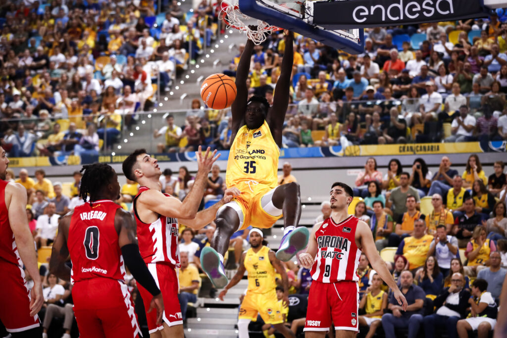 Jugador del Dreamland Gran Canaria realizando un mate ante la defensa rival, público animado.