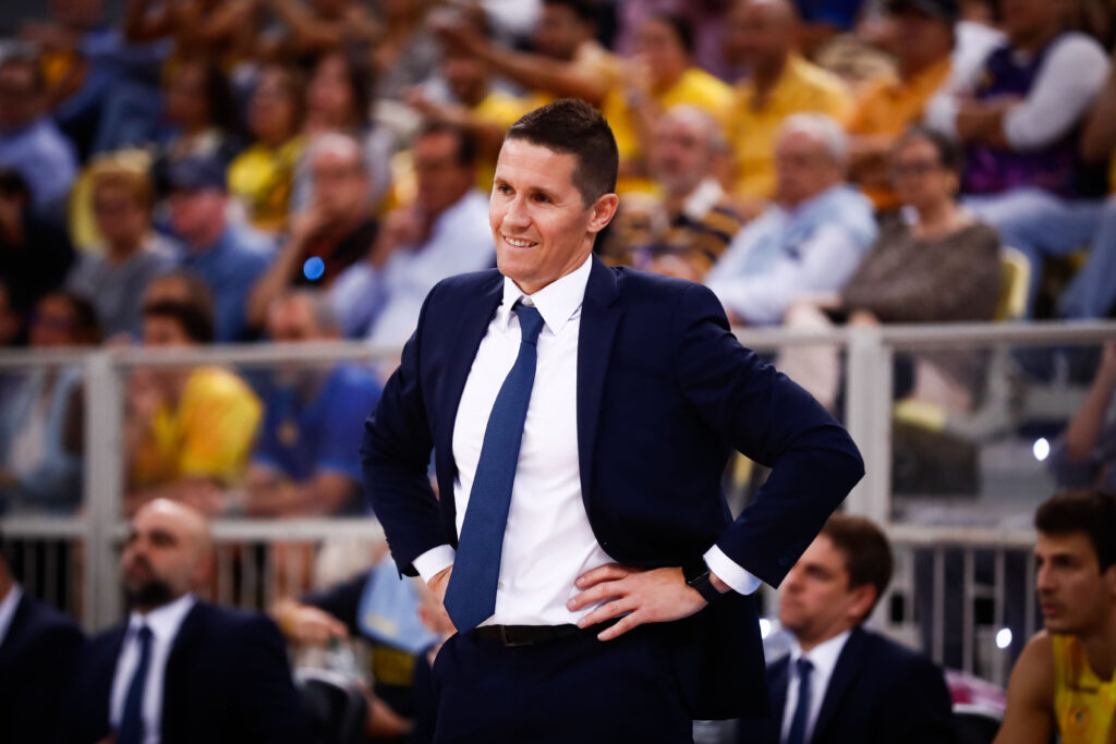 Entrenador del Dreamland Gran Canaria sonriente en un partido, rodeado de aficionados.