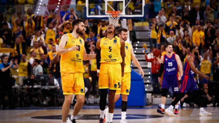 Jugadores del equipo celebran una jugada en un ambiente de emoción y apoyo del público.