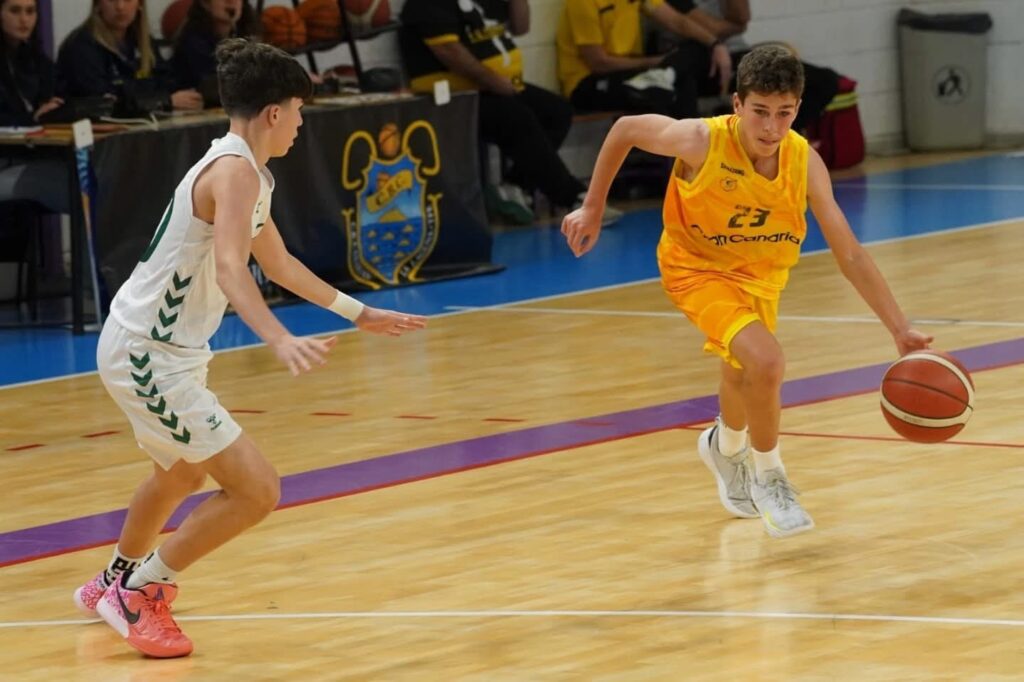 Infantil masculino en acción durante un partido de baloncesto, capturando un momento clave.