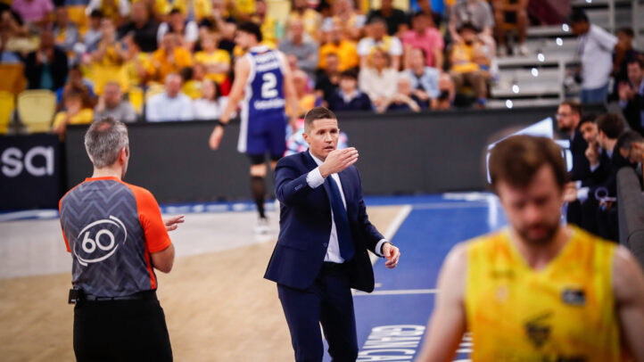 Entrenador dirigiendo al equipo en el banquillo durante un partido de baloncesto.