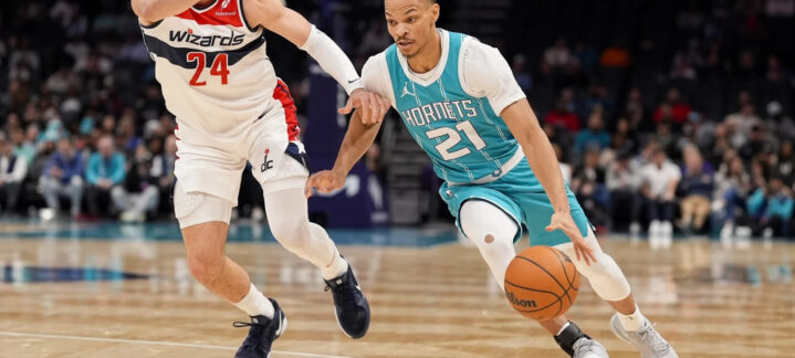 Jugador de los Hornets driblando el balón, mientras un rival intenta defenderlo.