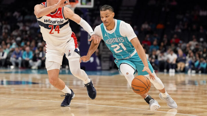 Jugador de los Hornets driblando el balón, mientras un rival intenta defenderlo.