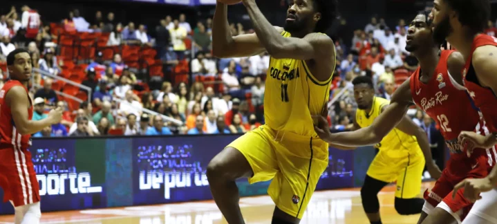 Jugador en acción durante un partido de baloncesto, intentando anotar frente a defensores.