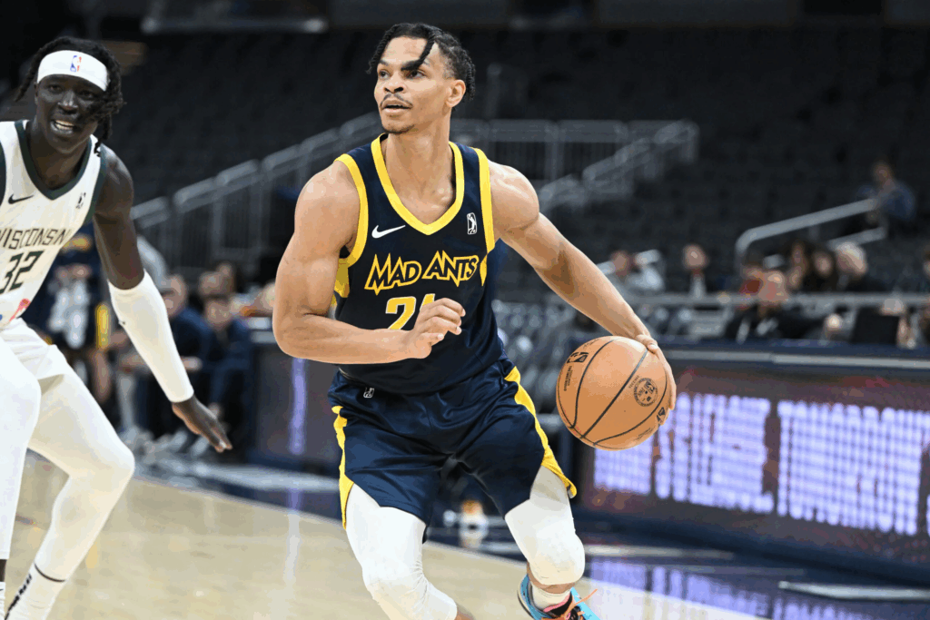 Jugador driblando con balón en un partido de baloncesto, con oponente a la vista.