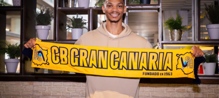 juego duro en defensa""",Jugador sostiene una bufanda del CB Gran Canaria con una sonrisa en un ambiente interior.