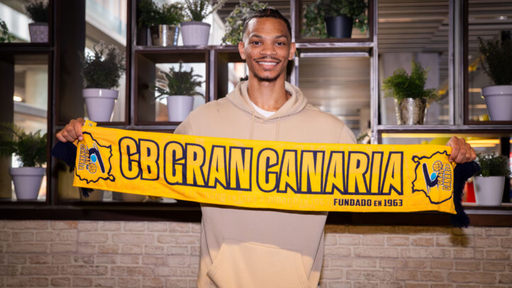 juego duro en defensa""",Jugador sostiene una bufanda del CB Gran Canaria con una sonrisa en un ambiente interior.