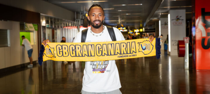 ya en la isla: ""Espero poder hacer algo importante con el equipo""",Jugador sosteniendo una bufanda del CB Gran Canaria en un aeropuerto.