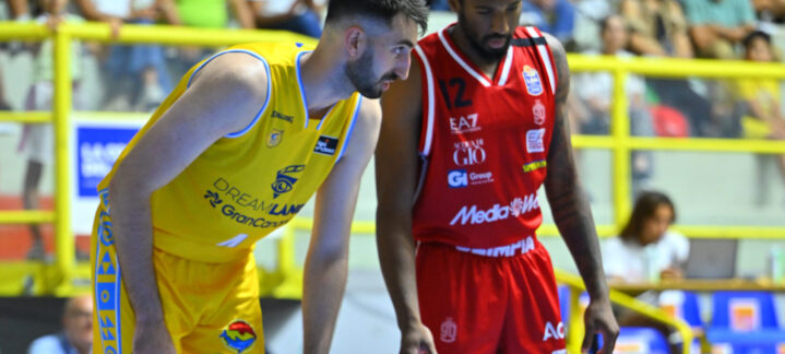 Dos jugadores de baloncesto en el campo, uno con camiseta amarilla y el otro en rojo.