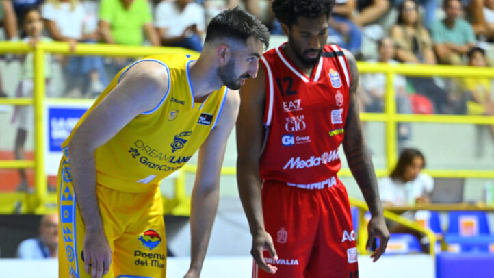 Dos jugadores de baloncesto en el campo, uno con camiseta amarilla y el otro en rojo.