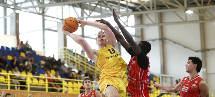 Fynn Schott lanza a canasta mientras es defendido por un rival durante un partido.