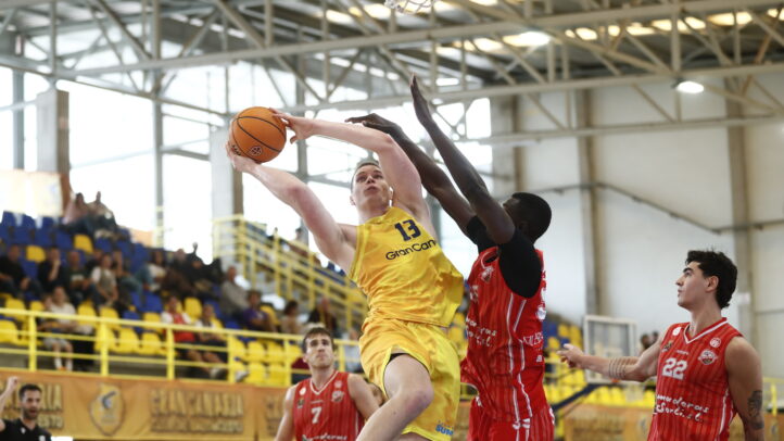Fynn Schott lanza a canasta mientras es defendido por un rival durante un partido.