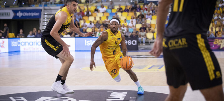Jugador del Dreamland Gran Canaria driblando con el balón durante un derbi de baloncesto.