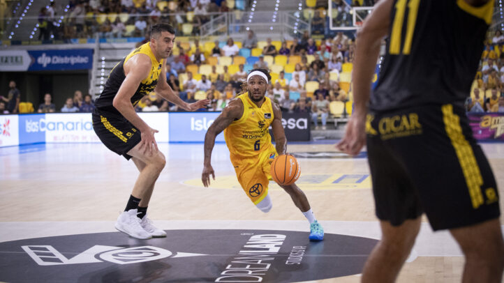Jugador del Dreamland Gran Canaria driblando con el balón durante un derbi de baloncesto.
