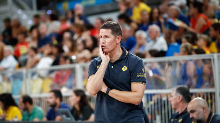 Entrenador Jaka Lakovic reflexionando durante un partido con afición al fondo.