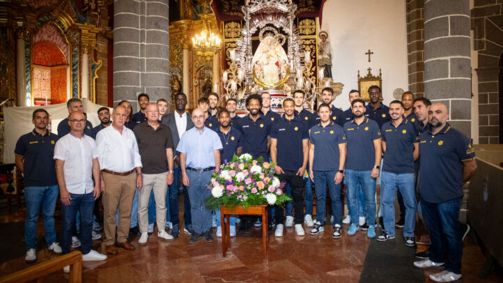 Jugadores y staff del Club Baloncesto Gran Canaria posan con una ofrenda floral.