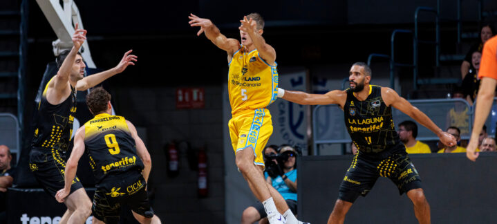 Jugadores en acción, lanzando un balón de baloncesto durante un partido competitivo.