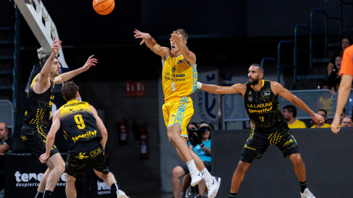 Jugadores en acción, lanzando un balón de baloncesto durante un partido competitivo.