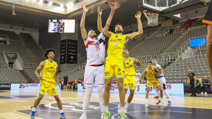 Jugadores compiten en un partido de baloncesto, con el equipo amarillo atacando.