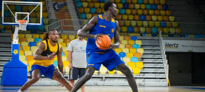 Jugadores del Gran Canaria entrenan en la pista, un balón de baloncesto en acción.