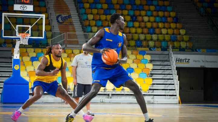 Jugadores del Gran Canaria entrenan en la pista, un balón de baloncesto en acción.