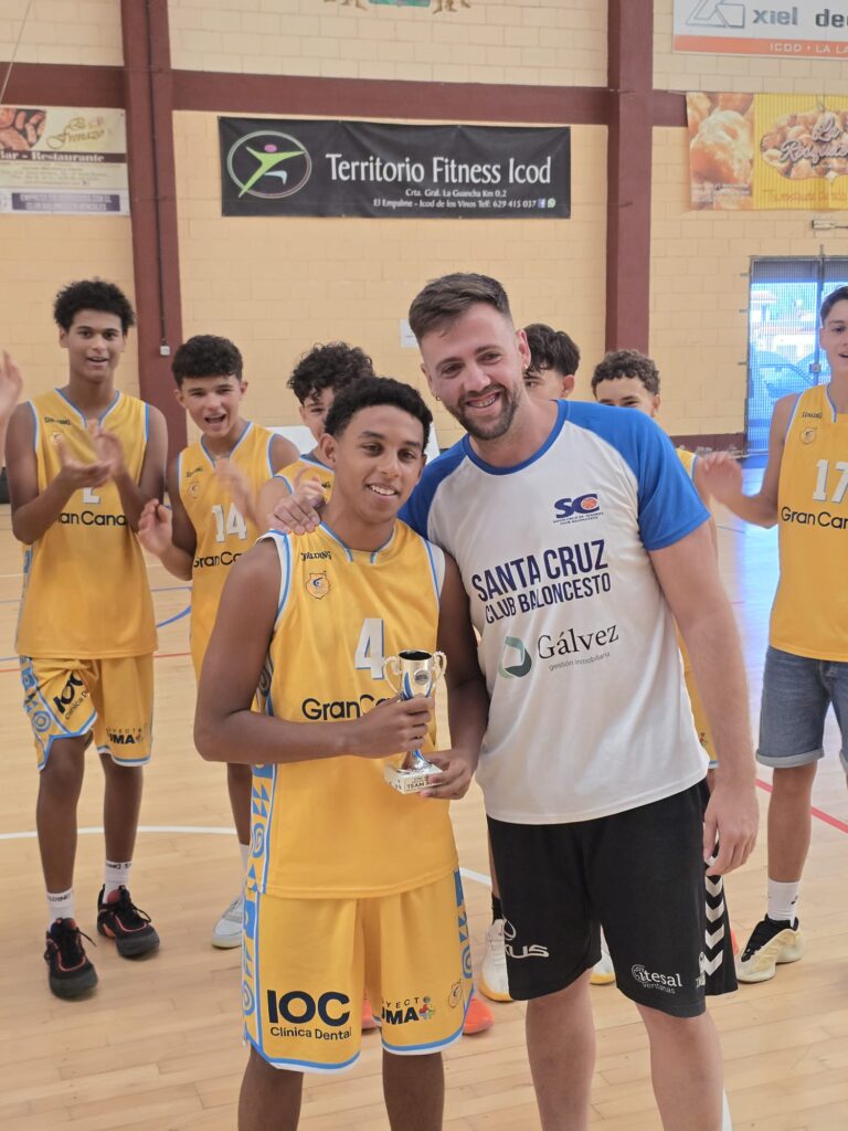 Niño con trofeo en mano posa con entrenador, celebrando un triunfo deportivo.