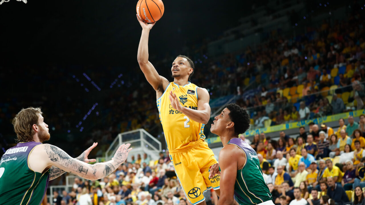 Baloncestista del Gran Canaria lanza a canasta ante dos defensores de Unicaja.