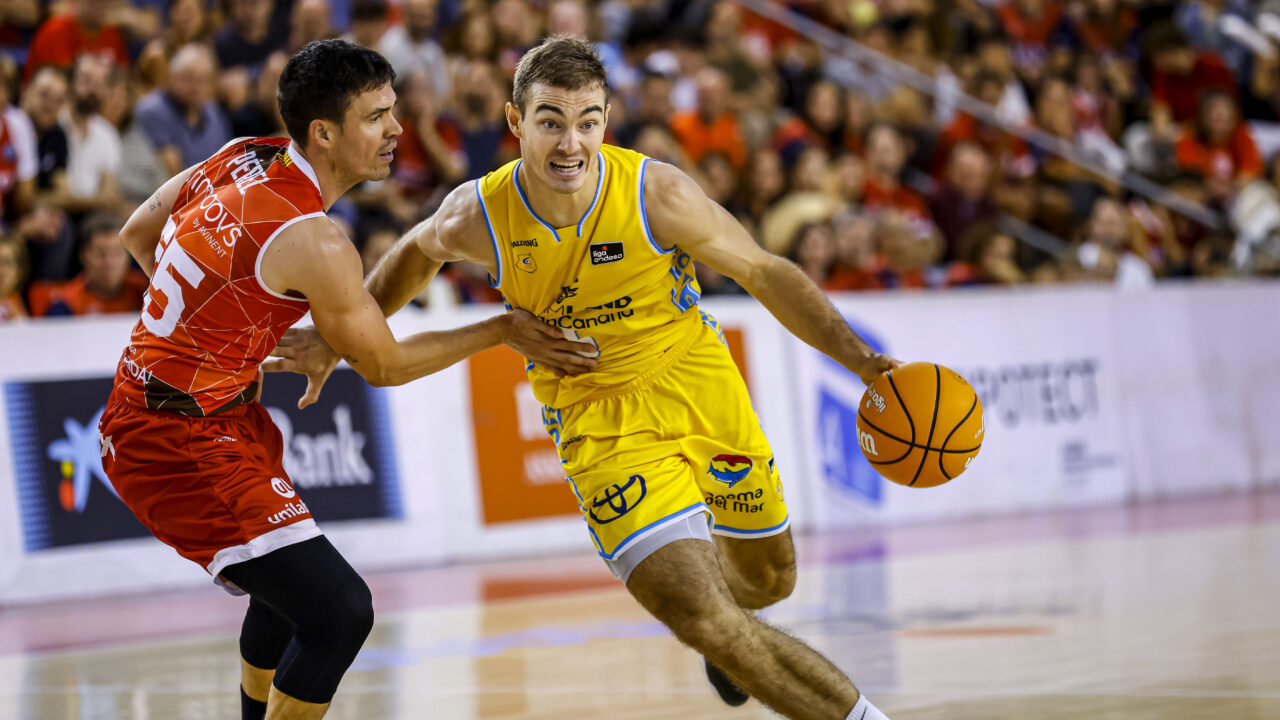 Jugador del Club Baloncesto Gran Canaria avanza con el balón, defendido por un rival.