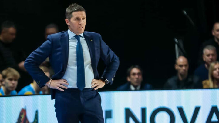 Entrenador de baloncesto observando el juego en un partido, con una actitud concentrada.