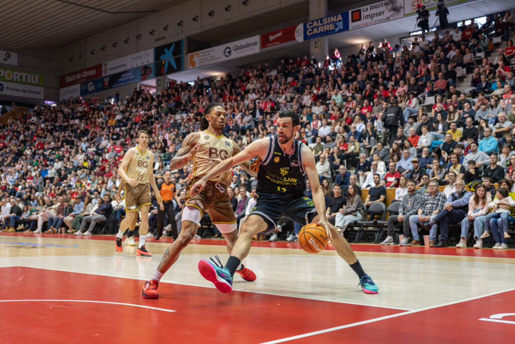Jugadores de baloncesto compiten en un partido con gran afluencia de público.