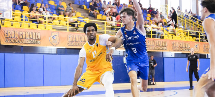 Jugadores de baloncesto compiten en la cancha, mientras uno dribla el balón.