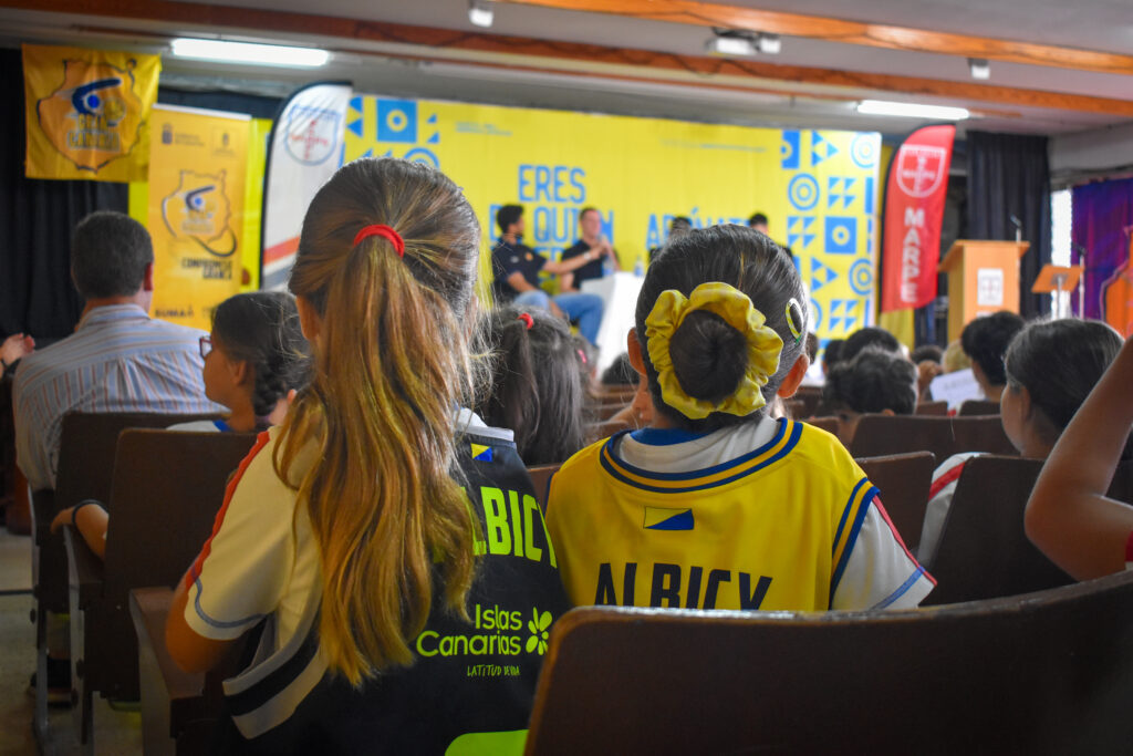  juntos en una mañana de sonrisas y cariño","Niñas en la audiencia, usando camisetas del Club Baloncesto Gran Canaria, en un evento.
