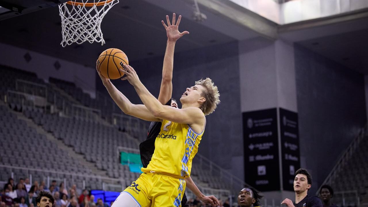 Jugador del Gran Canaria anotando una canasta mientras es defendido por un oponente.